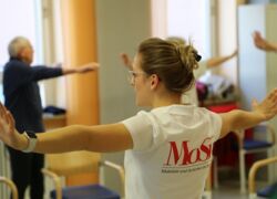 Trainerin aktiv bei Bewegungseinheit mit Seniorengruppe